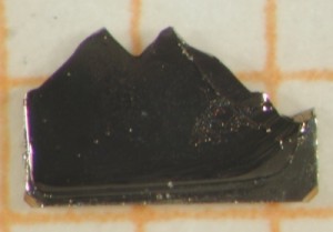 Einkristall der ternären Verbindung YbRh2Si2. Diese "Bergprobe" war die erste, an der die Supraleitung gefunden wurde. Skala: 1 mm. Foto: AG Krellner 
