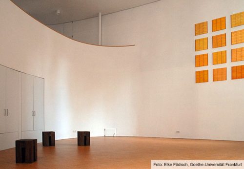 Drei Hocker vor einer Wand im Haus der Stille.