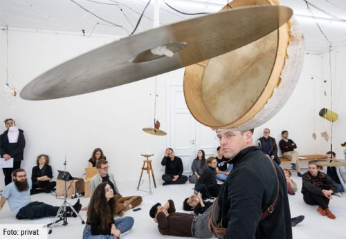 Menschen beim Workshop auf den Donaueschinger Musiktagen. Diverse Schlagzeug-Becken hängen von der Decke herab. Foto: privat